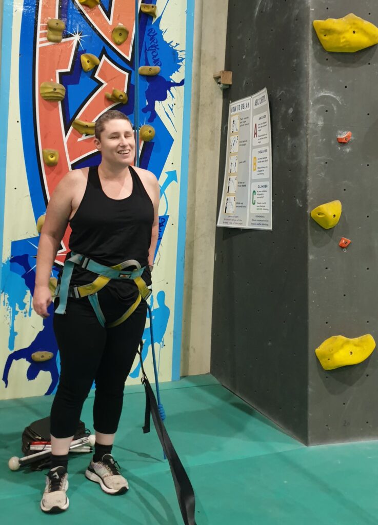 Danielle smiling broadly after climbing the wall at indoor rock climbing