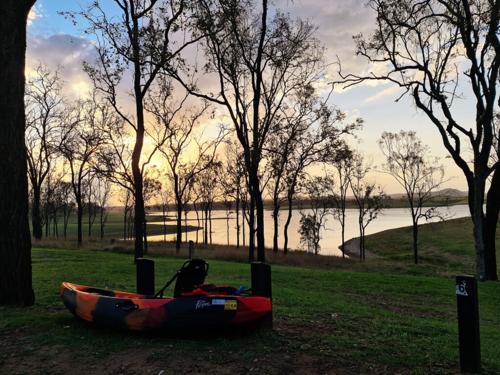 Damian's kayak alongside the campsite with the lake and sunset in the background